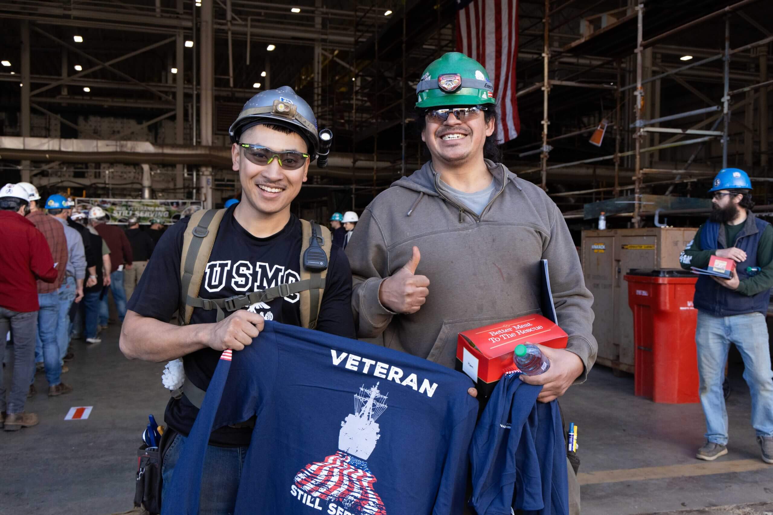 Two male BIW shipbuilders receive lunch and shirt for veterans day