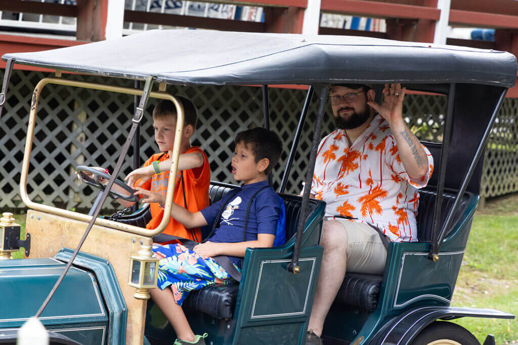 Family of three rides antique cars during BIW Family Day